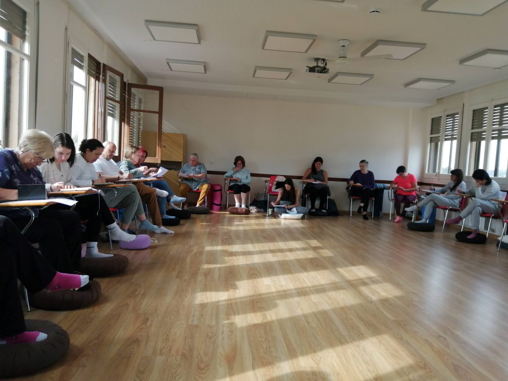 Participantes sentados en una sala, varios de ellos escribiendo en sus cuadernos