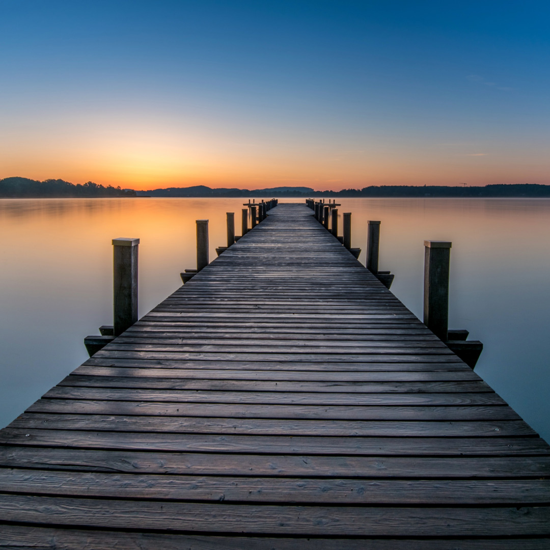 Pasarela de madera al amanecer Pasarela de madera hacia un lago al amanecer, imagen simbólica de quietud